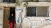 FILE - A Palestinian refugee woman living in Jordan wears a traditional Palestinian dress as she poses in front of her home at Al-Baqaa Palestinian refugee camp, near Amman, Jordan, June 16, 2020.