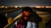 FILE - Cuban migrant Mario Perez holds his wife as they wait to be processed to seek asylum after crossing the border into the United States on Jan. 6, 2023, near Yuma, Ariz. 