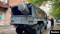 Sisa dari rudal pasukan Rusia dimasukan ke dalam kendaraan Kementerian Tanggap Darurat Ukraina yang berada di dekat sebuah gedung apartemen di Zaporizhzhia, yang hancur diserang oleh rudal Rusia, pada 21 Oktober 2022. (Foto: State Emergency Service of Ukraine/Handout via Reuters)