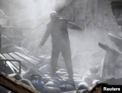 A man stands on the rubble of damaged buildings after an airstrike on the rebel-held town of Mesraba in the eastern Damascus suburb of Ghouta, Syria, Nov. 26, 2017.