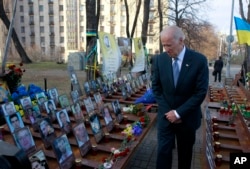FILE - U.S. Vice President Joe Biden pays his respects at a memorial honoring dozens of demonstrators killed during 2013-1014 anti-government protests in Kyiv, in Ukraine's capital, Dec. 7, 2015.
