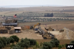 FILE - Vehicles and structures of U.S.-backed Kurdish forces are seen in the northern Syrian town of Manbij, May 8, 2018.