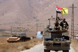 FILE - Hezbollah and Syrian flags flutter on a military vehicle in Western Qalamoun, Syria, Aug.&nbsp;28, 2017.
