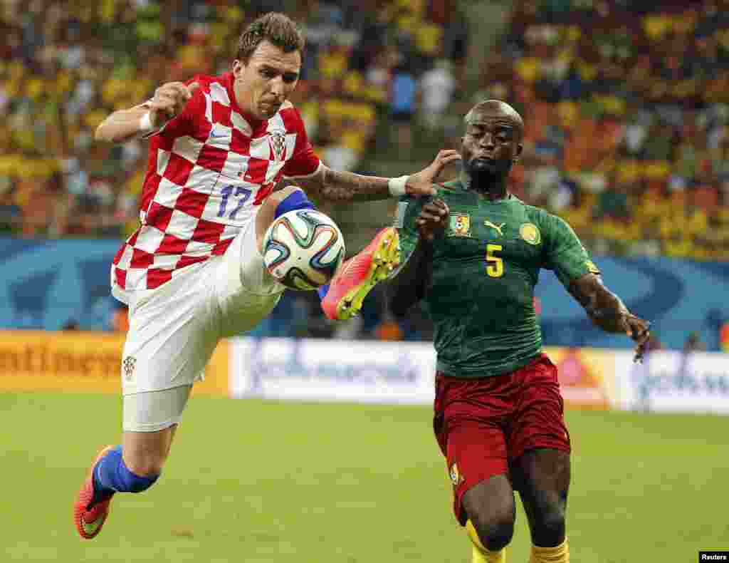 Croatia's Mario Mandzukic (left) fights for the ball with Cameroon's Dany Nounkeu during their 2014 World Cup Group A soccer match at the Amazonia arena, in Manaus, June 18, 2014.