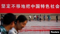 Warga melintas di depan slogan propaganda dalam peringatan 23 tahun tragedi di Lapangan Tiananmen, Beijing(3/6). 
