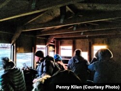As the sun rises, crane watchers look out the holes in the blinds at Aububon's Rowe Sanctuary to spot sandhill cranes perched on the river or flying overhead, near Gibbon, Neb., March 16, 2019.