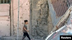 A girl walks on debris in a rebel-held part of the southern city of Deraa, Syria, July 9, 2017. 