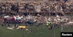 FILE - Police and rescue workers stand near a building which was destroyed in a massive explosion at a fertilizer plant in the town of West, near Waco, Texas, April 18, 2013.
