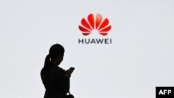 (FILES) This file photo taken on March 6, 2019 shows a staff member of Huawei using her mobile phone at the Huawei Digital Transformation Showcase in Shenzhen, China's Guangdong province.