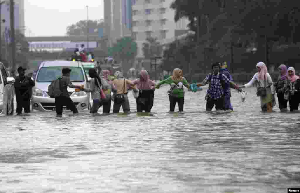 Workers cross a flooded street in the business district in Jakarta, Indonesia, January 17, 2013.