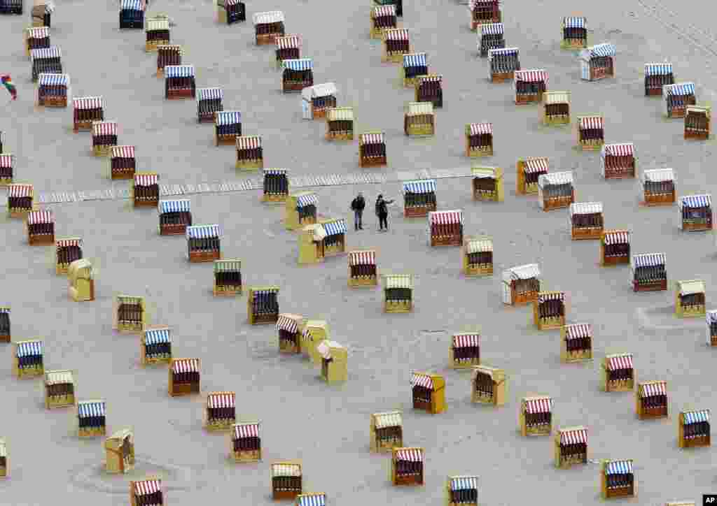 Two tourists walk between empty beach chairs at the Baltic Sea in Travemuende, northern Germany.