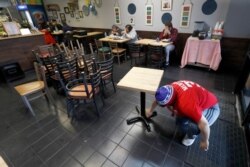 Restaurant manager Natalie Marquez sanitizes tables and stacks chairs in Chicago, March 16, 2020.
