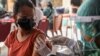 Seorang perempuan menerima satu dosis vaksin AstraZeneca COVID-19 saat program vaksinasi massal untuk Kawasan Wisata Hijau di Sanur, Bali, 23 Maret 2021. (Foto: REUTERS/Nyimas Laula)