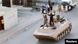 Pejuang militan Islam mengibarkan bendera kelompok ISIS saat ikut dalam parade militer di sepanjang jalan provinsi Raqqa utara, Suriah, 30 Juni 2014.