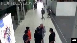 In this image made from airport closed circuit television video and provided by Fuji Television, Kim Jong Nam, exiled half-brother of North Korea's leader Kim Jong Un, gestures towards his face while talking to airport security and officials at Kuala Lump