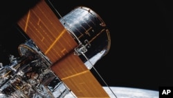 FILE - In this photograph provided by NASA, most of the giant Hubble Space Telescope can be seen as it is suspended in space by the shuttle Discovery's Remote Manipulator System following the deployment of part of its solar panels and antennae, April 25,