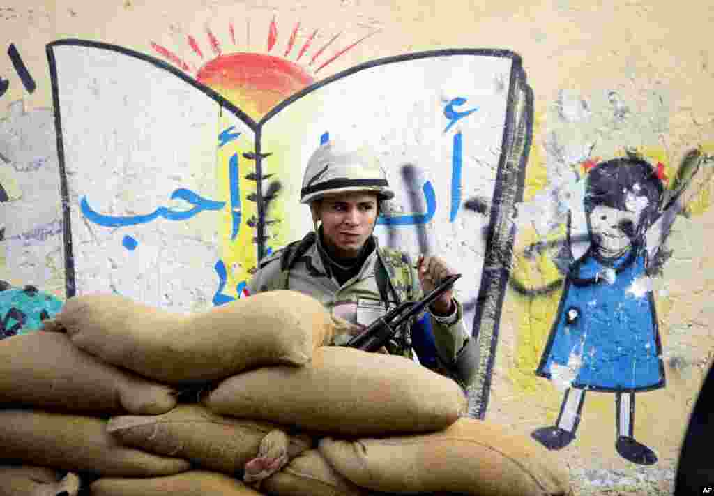 A soldier stands behind a protective barrier of sand bags outside a polling station in Cairo, Jan. 14, 2014.