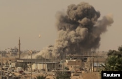FILE - Smoke rises after an airstrike during fighting between members of the Syrian Democratic Forces and Islamic State militants in Raqqa, Syria, Aug. 15, 2017.