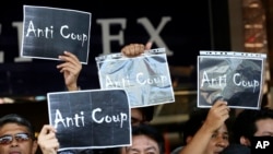 Thai anti-coup protesters hold up banners during a protest outside a shopping complex in Bangkok, Thailand Saturday, May 24, 2014.