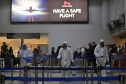 Workers wearing protective gear spray disinfectant as a precaution against the coronavirus outbreak, in the departure terminal at the Rafik Hariri International Airport, in Beirut, Lebanon, Thursday, March 5, 2020.