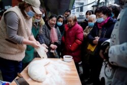 People wearing protective masks wait to buy food at a street market almost a year after the start of the coronavirus disease (COVID-19) outbreak, in Wuhan, Hubei province, China December 7, 2020. Picture taken December 7, 2020. REUTERS/Aly Song
