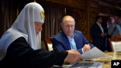 Russian President Vladimir Putin, with Russian Orthodox Patriarch Kirill, left, speak in the library of the Russian monastery St. Panteleimon at Karyes, on Mount Athos, Greece, May 28, 2016.
