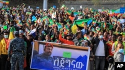 FILE - People gather behind a placard showing Prime Minister Abiy Ahmed at a rally organized by local authorities to show support for the Ethiopian National Defense Force (ENDF), at Meskel square in Addis Ababa, Ethiopia, Nov. 7, 2021.
