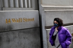 A person wearing a face mask walks along Wall Street after further cases of coronavirus were confirmed in New York City, New York, U.S., March 6, 2020.