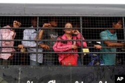 Buruh migran Kamboja berdiri di atas truk saat mereka tiba dari Thailand di gerbang perbatasan internasional Kamboja-Thailand di Poipet, Kamboja, Selasa, 17 Juni 2014. (Foto: AP)