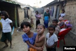 FILE - A Rohingya refugee girl carries a baby inside a refugee camp in Sitwe, in the state of Rakhine, Myanmar, March 4, 2017.
