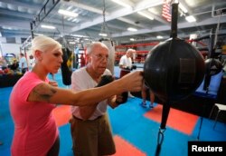FILE - Parkinson's patient Jim Coppula gets some pointers from his daughter Ellen as he works out on a bag during his Rock Steady Boxing class in Costa Mesa, California, Sept. 18, 2013.