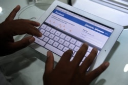 FILE - A Cambodian man logs into Facebook as he inspects the ipad 2 during an Apple store opening in Phnom Penh on September 9, 2011.
