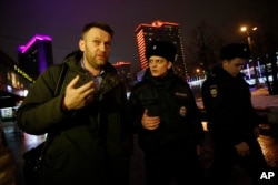 FILE - Russian opposition activist Alexei Navalny, left, is briefly detained by police after defying his house arrest to speak on Radio Ekho Moskvy in Moscow, Jan. 14, 2015.