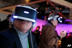 FILE - People look through Sony PlayStation VR headsets after a Sony news conference at CES International in Las Vegas, Jan. 8, 2018.