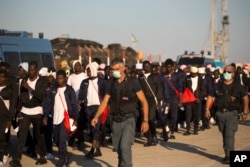Italian border police officers escort sub Saharan men on their way to a relocation center, after arriving aboard the Golfo Azzurro rescue vessel at the port of Augusta, in Sicily, Italy, June 23, 2017.