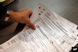 Tax professional and tax preparation firm owner Alicia Utley reaches for hard copies of tax forms at the start of the tax season rush in her offices in Boulder, Colo., Jan. 14, 2017.