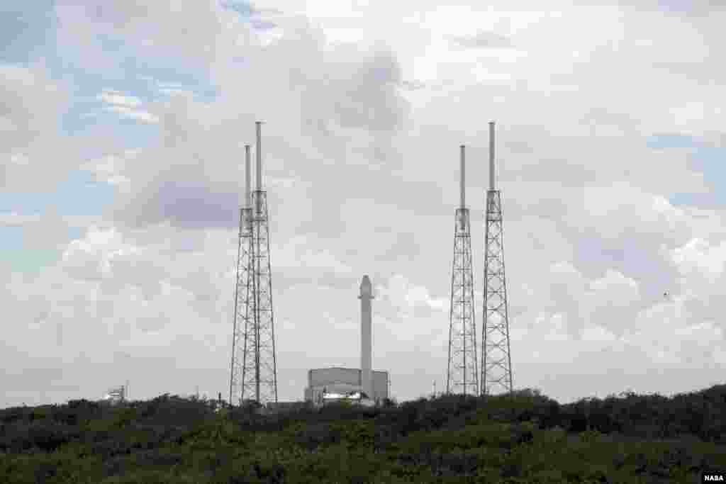 A Falcon 9 rocket with a Dragon capsule secured atop stands upright between the lightning masts on the pad at Space Launch Complex 40, Cape Canaveral Air Force Station, Florida, October 7, 2012. (NASA/Jim Grossmann)