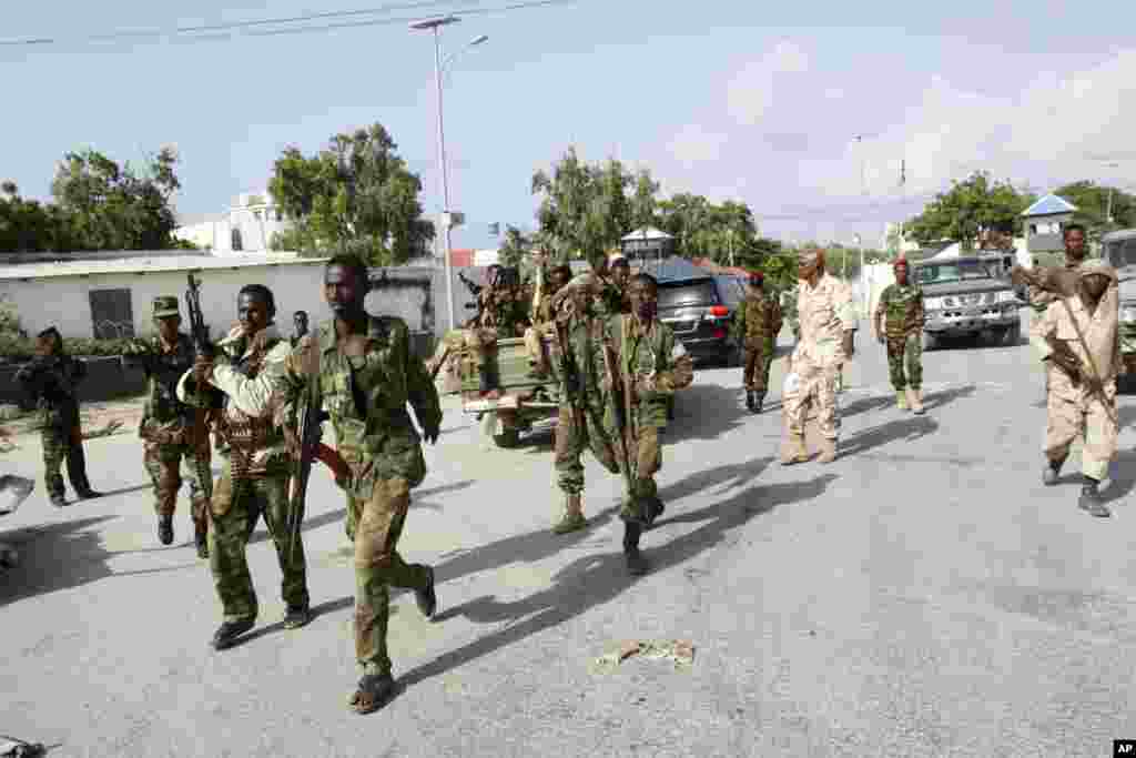 Somali soldiers patrol near the wreckage of a car bomb that was detonated at the main gate of the presidential palace in Mogadishu, July, 9, 2014.
