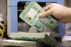 A man counts Lebanese pound banknotes at a currency exchange shop in Beirut, Jan. 5, 2022.