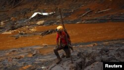 FILE - A rescue worker searches for victims at Bento Rodrigues district that was covered with mud after a dam owned by Vale SA and BHP Billiton Ltd burst, in Mariana, Brazil, Nov. 8, 2015. 