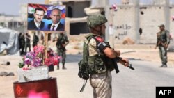 Members of Russian and Syrian forces stand guard near posters of Syrian President Bashar al-Assad and his Russian counterpart Vladimir Putin at the Abu Duhur crossing on the eastern edge of Idlib province, Aug. 20, 2018.
