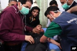 This photo released by the Syrian official news agency SANA shows medical staff treating a boy following a suspected chemical attack on his town of al-Khalidiya, in Aleppo, Syria, Nov. 24, 2018.