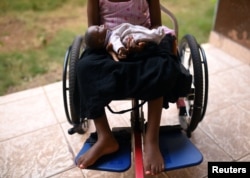 FILE - A five-year-old girl poses with her doll as she sits in her wheelchair in the courtyard of the Aberdeen Women's Center, one year after a sexual assault that her family says left her paralyzed, in Freetown, Sierra Leone, Feb. 7, 2019.