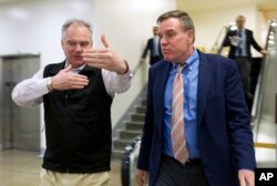 Sen. Tim Kaine, D-Va., speaks with Sen. Mark Warner, D-Va., as they walk to their offices Jan. 20, 2018, on Capitol Hill in Washington.