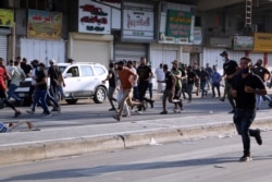 FILE - Supporters of Iraqi Shiite armed groups run from security forces after clashes during a protest against the election results in Baghdad, Iraq, Nov. 5, 2021.
