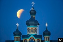 Fenomena yang dikenal sebagai supermoon tampak di akhir gerhana bulan di belakang geraja Ortodoks di Turets, Belarusia, 110 kilometer sebelah barat ibukota Minsk, Senin 28 September 2015.