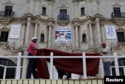 Workers do the final touches to one of the podiums near Havana's cathedral, that will be used during visit of Pope Francis, Cuba, Sept. 17, 2015.