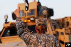 FILE - U.S. Army convoys are given the thumbs up from a fellow soldier after crossing into Kuwait during the last convoy out of Iraq.