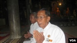 លោក​អាចារ្យ​យឹម​ វន បាន​ក្រោក​ពី​ព្រលឹម​មក​សូត្រ​យង្កិញ​នៅ​វត្ត​នន្ទមន្នី ដោយ​ភ្ជាប់​មក​ជា​មួយរូប​ព្រះ​ឆាយាល័ក្ស​ព្រះ​បាទ​សីហនុ​នៅ​លើ​អាវ​គាត់។ (ឃួន ធារ៉ា)