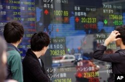 FILE- People look at an electronic stock indicator of a securities firm in Tokyo.
